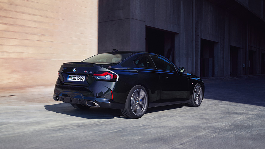 BMW M240i xDrive Coup&eacute; G42 2021 Black Sapphire metallic vue de trois quarts arri&egrave;re &agrave; l&rsquo;arr&ecirc;t devant entrep&ocirc;t